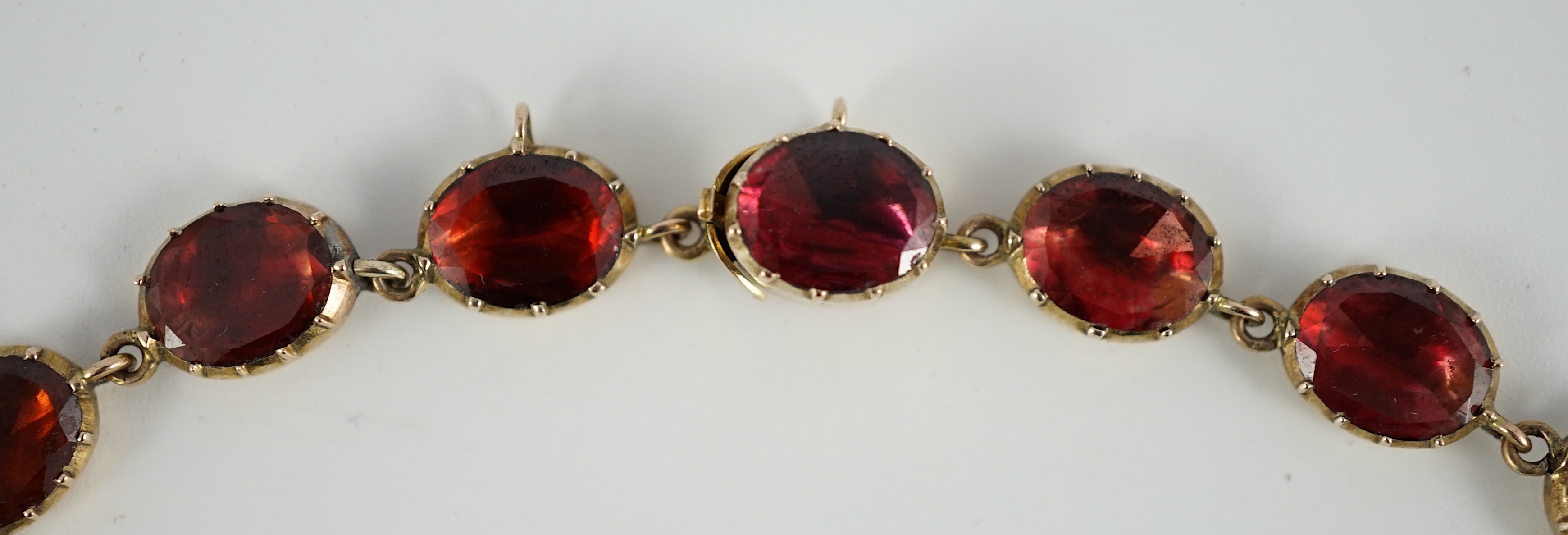 An early 19th century gold mounted graduated foil backed oval cut garnet set choker necklace